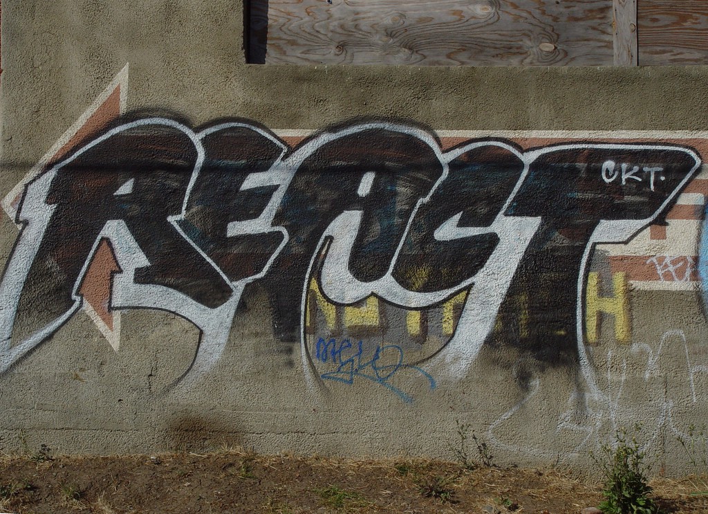 The word "react" spray-painted on a concrete wall.